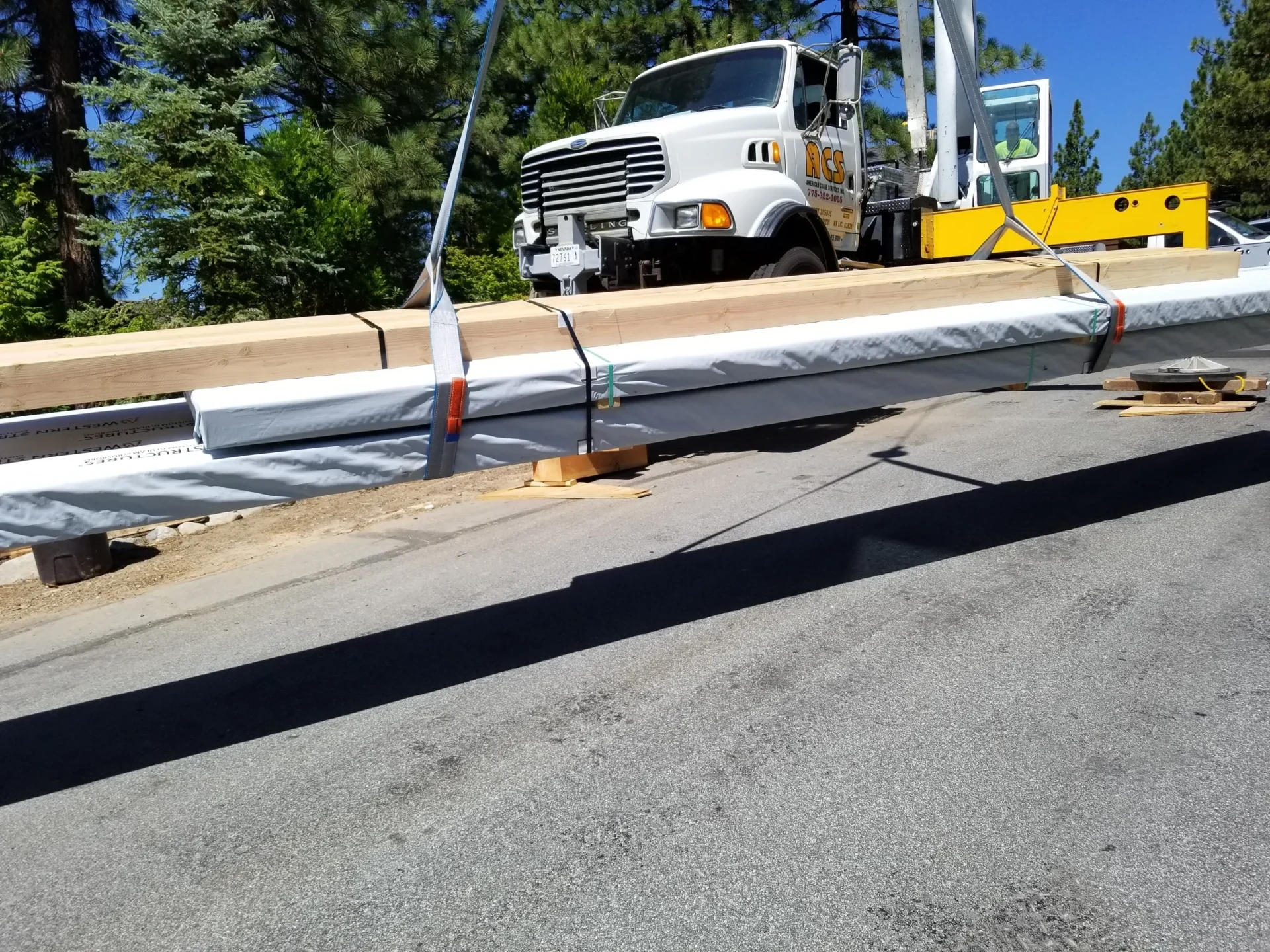 A crane is lifting a truck over the road.