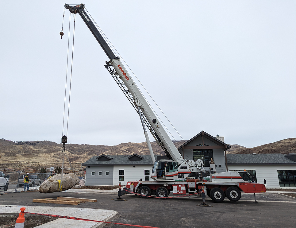 A crane is lifting a large rock into the air.