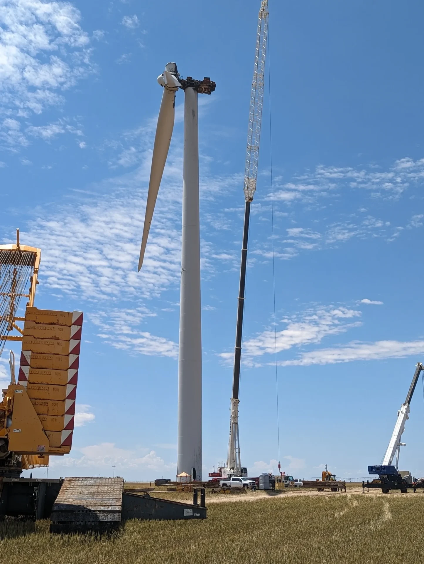 A crane is in the sky next to some wind turbines.