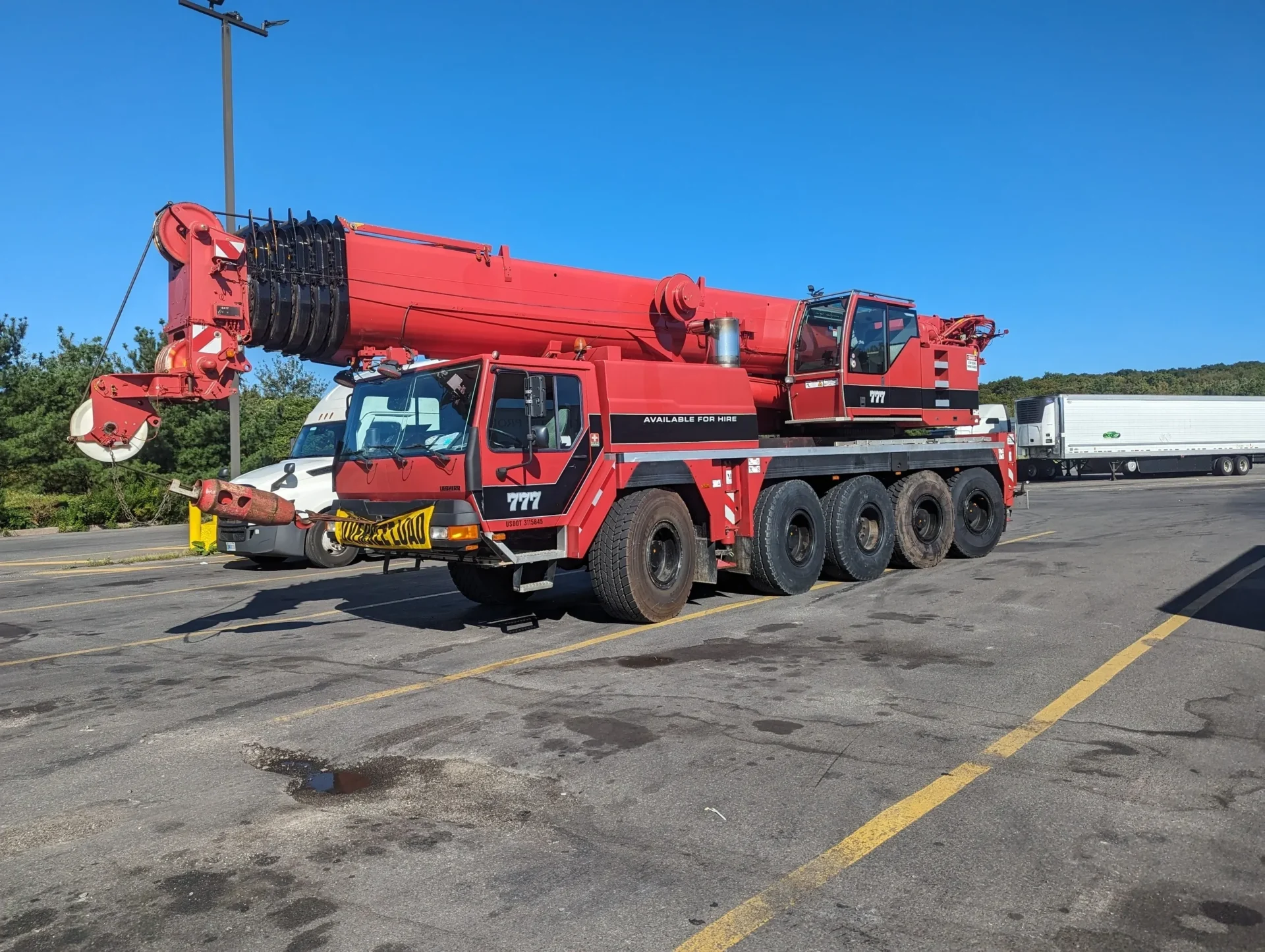 A large red crane sitting in the middle of a parking lot.