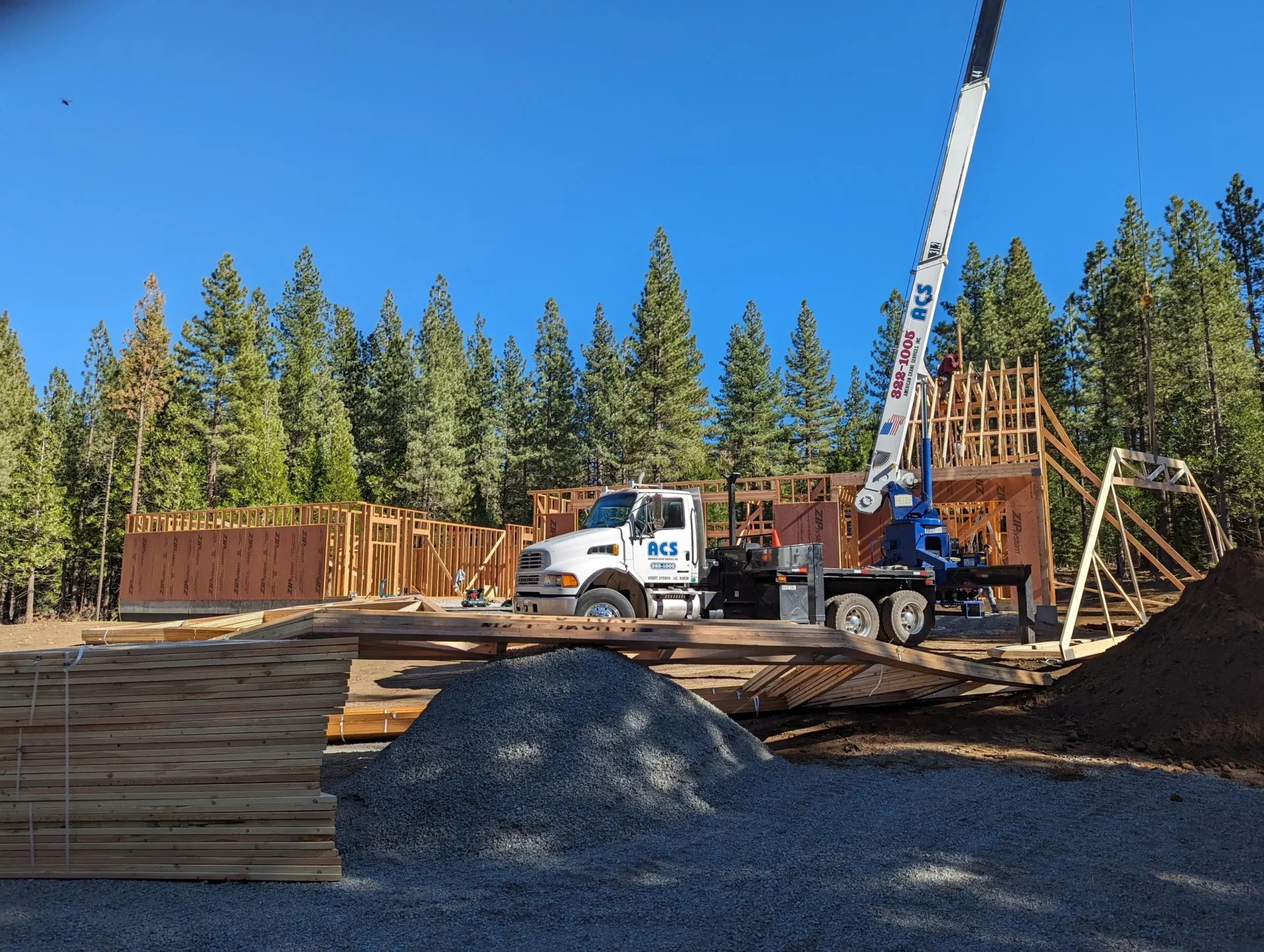 A crane is lifting wood on top of the ground.