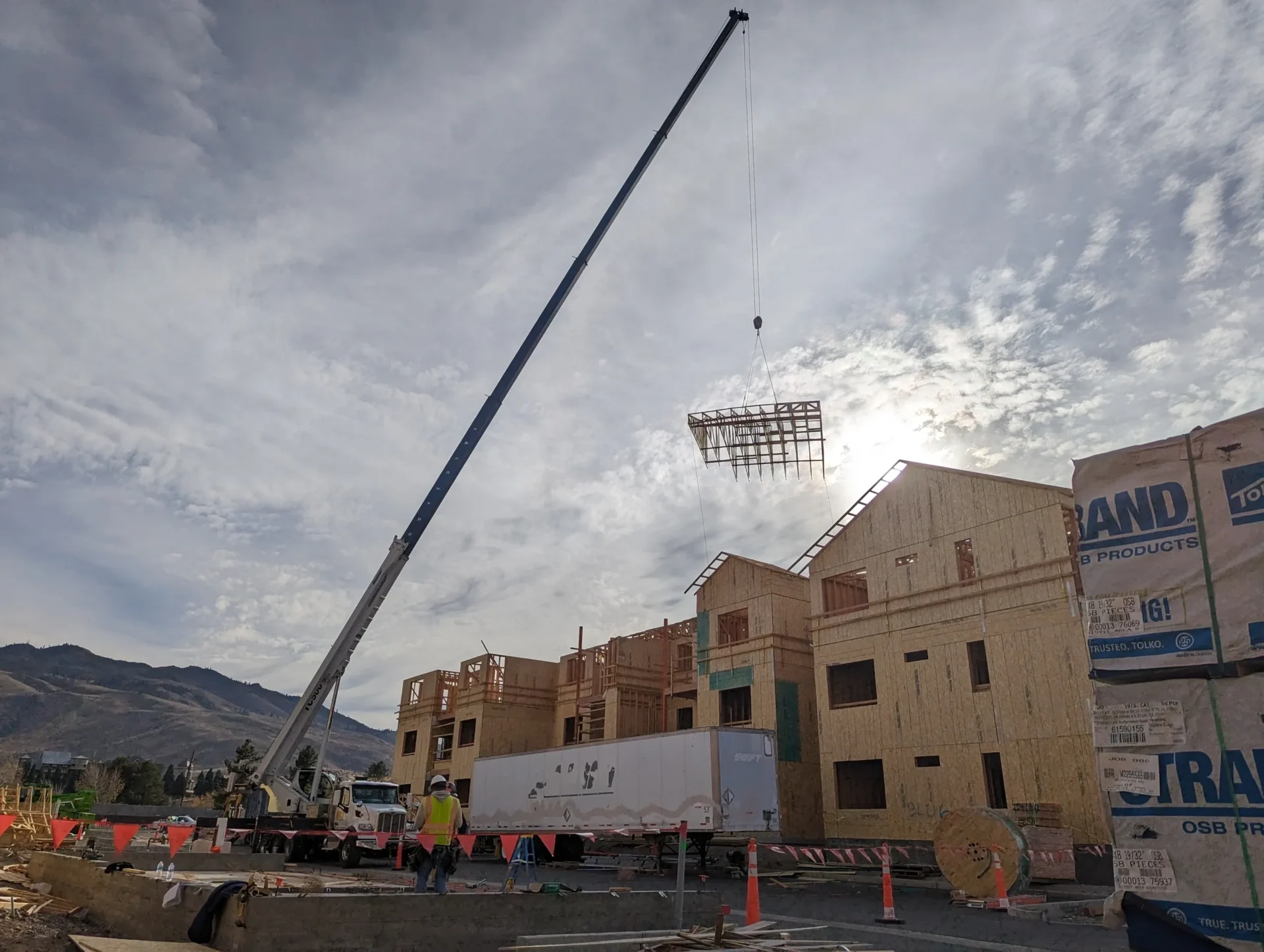 A crane is lifting up the roof of a building.