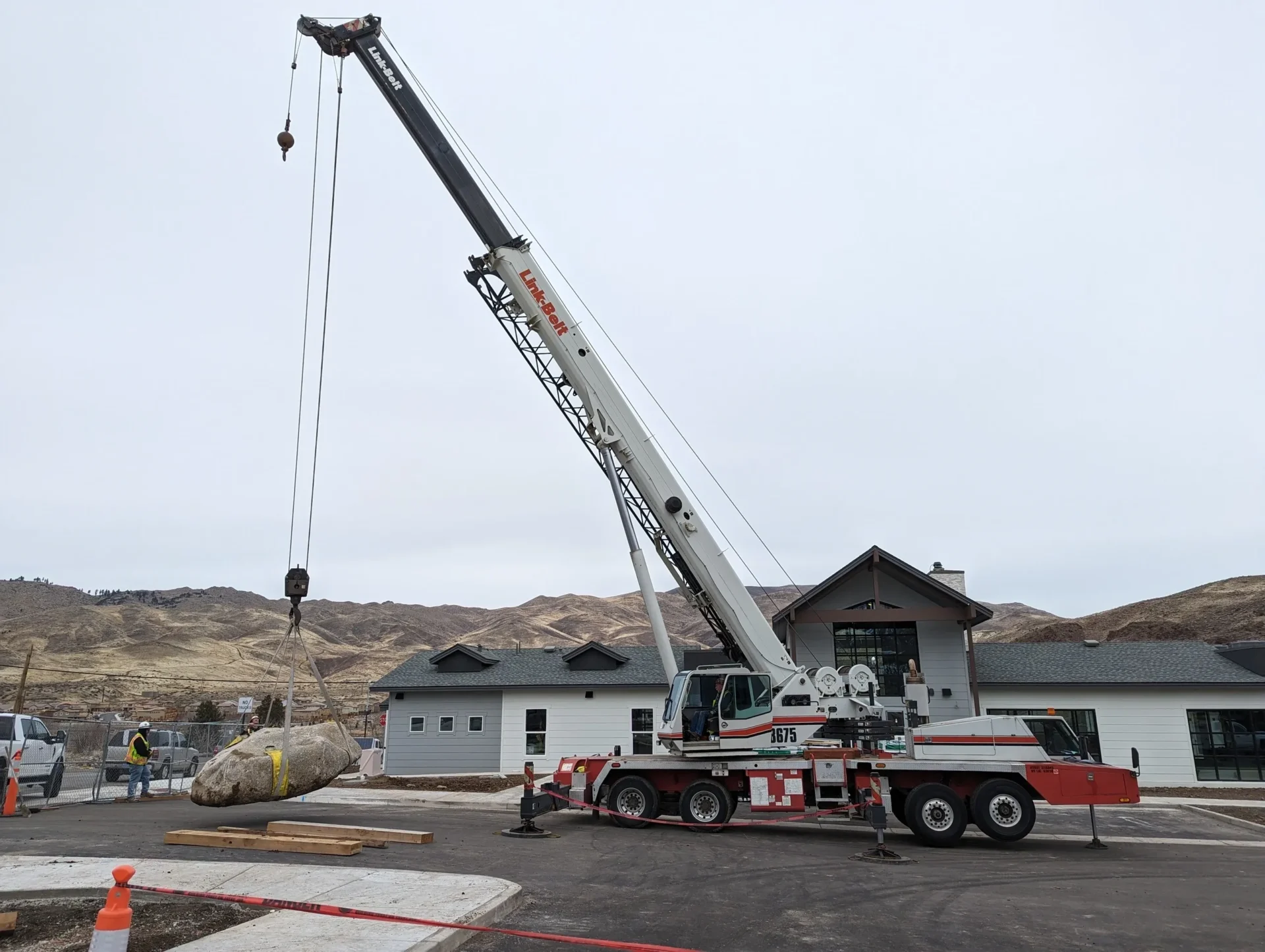 A crane is lifting a rock into the air.