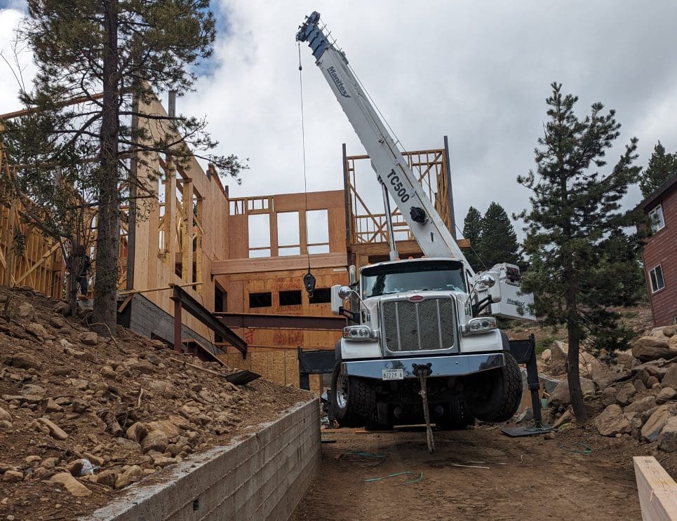 A crane is in front of a house being built.