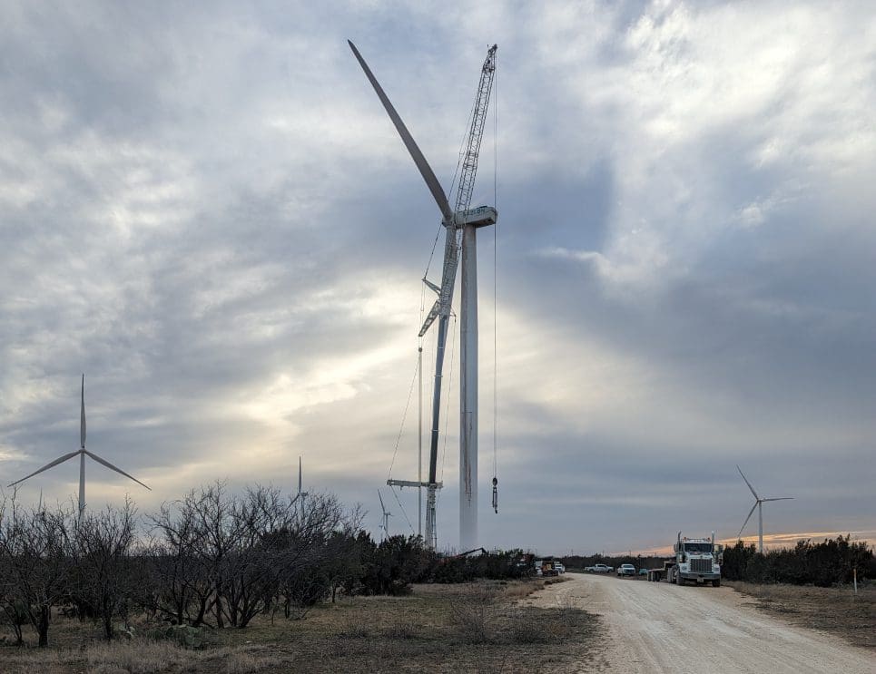 A wind turbine is being built on the side of a road.